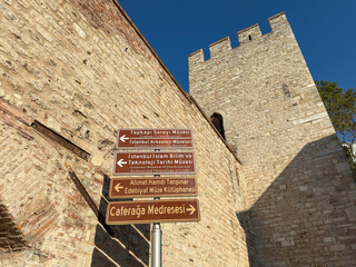Stone fortress wall of Gulhane Park with direction signs pointing to museums and heritage sites
