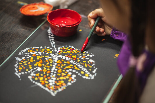 A kids sit at a table, joyfully drawing autumn themed pictures. Surrounded by a colorful array of pencils, markers, and pens