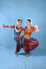 Indian female dancers in beautiful costumes on a blue background in the studio in dance poses