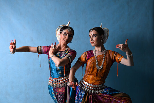 Indian female dancers in beautiful costumes on a blue background in the studio in dance poses
