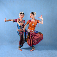 Indian female dancers in beautiful costumes on a blue background in the studio in dance poses
