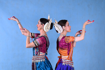 Indian female dancers in beautiful costumes on a blue background in the studio in dance poses