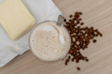 A cup of coffee for breakfast with butter and coffee beans around it, bulletproof coffee