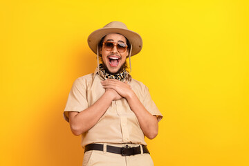 Happy explorer in safari style outfit poses with big smile yellow background travel adventure...
