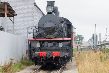 A steam locomotive on a siding next to a grey fence