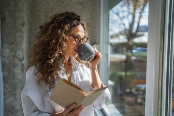 Woman enjoying morning coffee and reading book at home