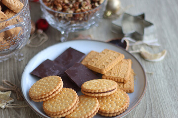 Various Christmas decorations, cookies, chocolate and nuts on wooden background. Selective focus.