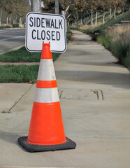 Orange pylon with sidewalk closed sign attached