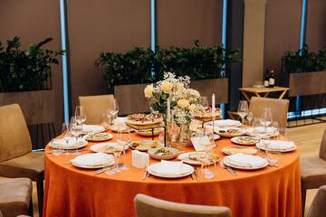 Elegant banquet table with floral centerpiece, candles and appetizers in restaurant