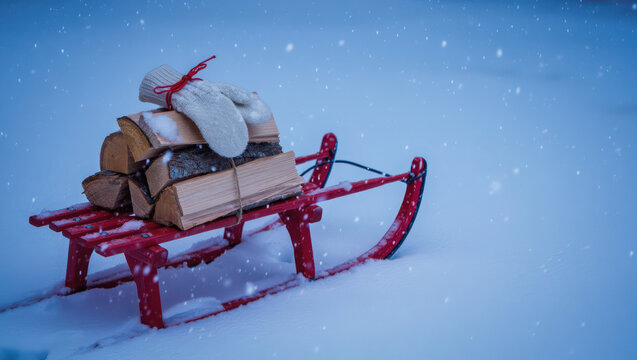 Nostalgic scene with an antique wooden sled sitting in a blanket of fresh, pristine snow under the gentle snowfall. A bundle of chopped firewood and a pair of fuzzy winter mittens rest on the sleigh