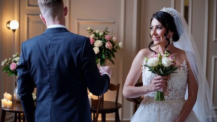 bride and groom share first look in elegant indoor suite, bride holding bouquet with white roses, delicate