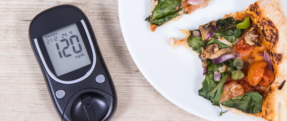Glucometer with result of sugar level and fresh baked vegetarian pizza. Nutrition during diabetes