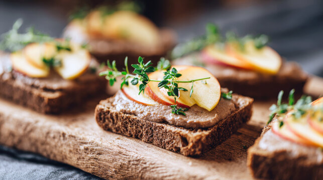 Rich and creamy chicken liver pate or rustic rillette spread on dark rye bread, garnished with crisp apple slices and aromatic thyme. A perfect, sophisticated appetizer or snack
