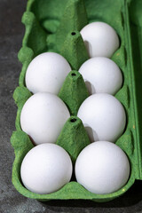 Fresh white eggs placed in a green carton ready for cooking or baking in a kitchen setting