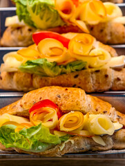 Artisan gourmet sandwich with cheese rosettes, crisp lettuce and multigrain bread – premium bakery deli food photography