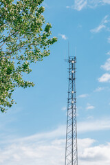 Telecommunication Tower with Green Tree Against Blue Sky