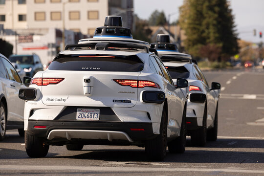Belmont, California, USA - October 30, 2025: Two Waymo self driving robotaxi cars stop at a stop light.
