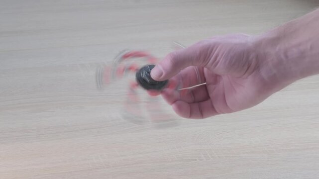 Young man using spinner toy, man hand playing with transformer spinner, physical therapy, building strength, improving mobility, relaxing after daily stress, Male wrist rehabilitation exercise