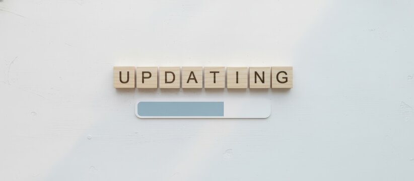 Wooden letter blocks spell updating above a progress bar on a clean white interface, symbolizing software updates, downloads, system upgrades, installation, and digital progress