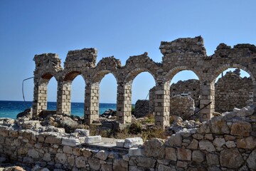 Ruins of an old industrial building made of stone, located by the Aegean Sea in Samos, Greece. Historical coastal architecture and abandoned structure concept.