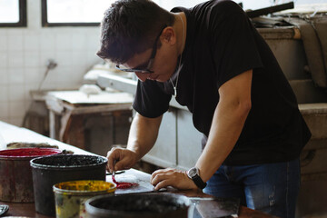 Man diluting lithography ink in a workshop, focusing on the refined manual process of traditional printmaking