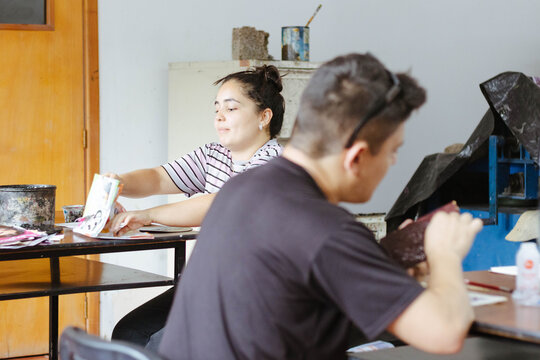 Art students developing creative skills in craft workshop class, learning graphic arts and printmaking