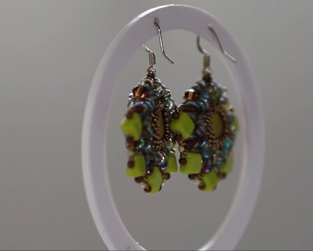 Nahaufnahme handgefertigter Ohrringe mit kleinen Perlen, die kunstvoll in sanftem Licht pr&auml;sentiert werden