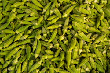Fresh okra pile at local market. Heap of green okra on market stall. Organic okra displayed at...