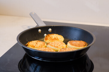 Hot golden cottage cheese pancakes syrniki freshly cooked on a frying pan