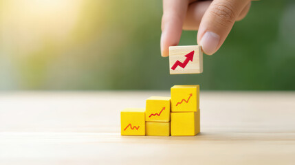 Hand placing wooden block with red upward arrow on top of yellow blocks with similar arrows, symbolizing growth and progress in business or finance