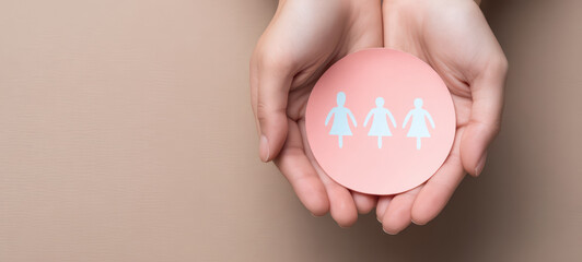 Hands gently holding pink paper circle with three white female figures symbolizing women empowerment and unity, set against soft beige background creating calm and supportive atmosphere