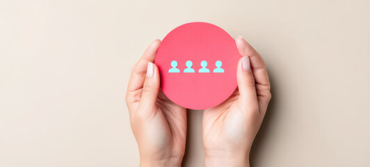 Hands gently holding red paper circle with four blue human icons symbolizing teamwork and connection, conveying unity and collaboration in soft beige background
