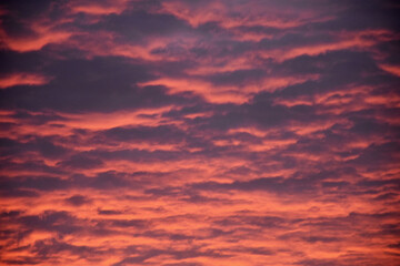 Dramatic red and pink autumn or winter sky at sunset or dusk with layers of grey cloud receding into the distance. Natural abstract pattern and texture
