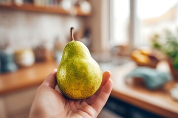 Hand holding fresh green pear in kitchen