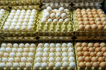 Brown and white eggs arranged on market counter. Local farm fresh eggs sold at outdoor market. Organic farm eggs for sale at farmers market.