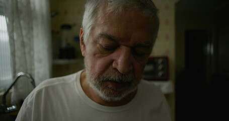 Close-up of elderly man in kitchen with introspective expression, representing solitude, aging, and moments of quiet reflection in domestic life