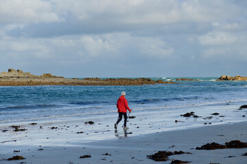 Une femme senior qui marche sur une plage en Bretagne