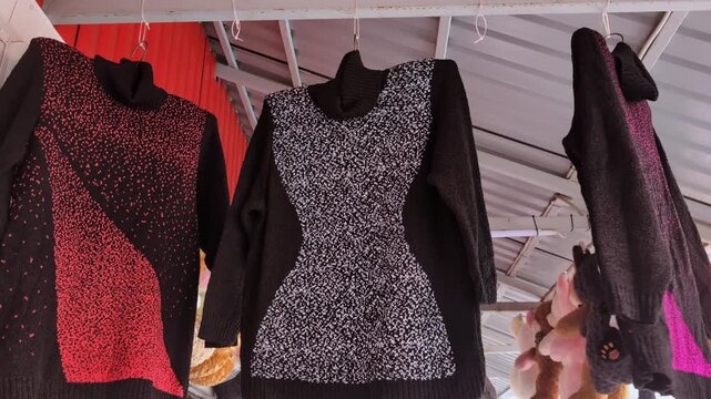 Fashion collection showcase of colorful sweaters in a vibrant market setting during late afternoon hours