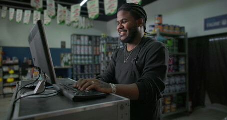 Smiling young man working at a computer in a paint store, engaging with customers and managing inventory, representing professionalism and friendly service in retail
