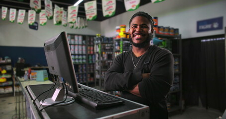 Smiling young man working at a counter in a paint store, confidently engaging in customer service and store management, representing professionalism and retail excellence