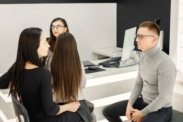 Optometrist helping family choosing glasses in optics store