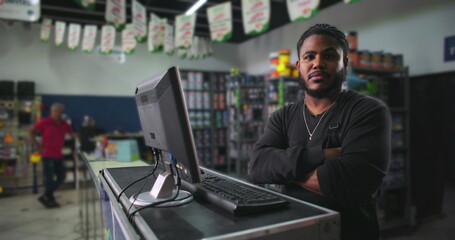 Serious young man standing at a counter in a paint store, arms crossed and focused, representing determination, professionalism, and a strong work ethic in retail