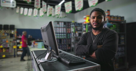 Serious young man standing at a counter in a paint store, arms crossed and focused, representing determination, professionalism, and a strong work ethic in retail