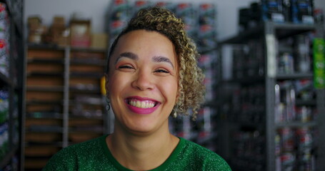 Smiling woman in a retail store, standing in front of shelves stocked with paint cans, expressing positivity and professionalism in a workplace environment