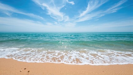 A serene beach scene with sand, gentle waves, and a partly cloudy sky.