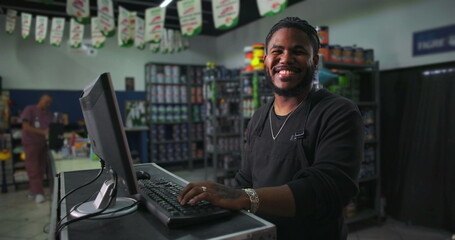 One Smiling Black store clerk interacting with customers, computer on desk in a well-organized retail shop, positive customer service and approachable demeanor