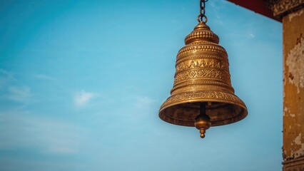 Fototapeta premium A large, ornate bell hanging from a chain against a blue sky background.