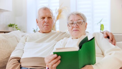 Elderly couple reading a book together at home during the Christmas season