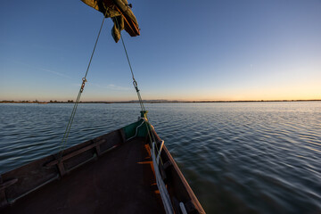 Traditional wooden boat navigating albufera lake at sunset