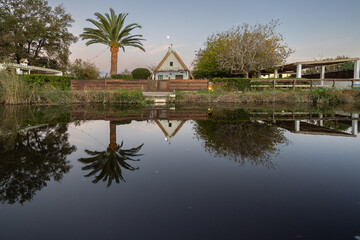Albufera lake reflecting traditional house and palm tree